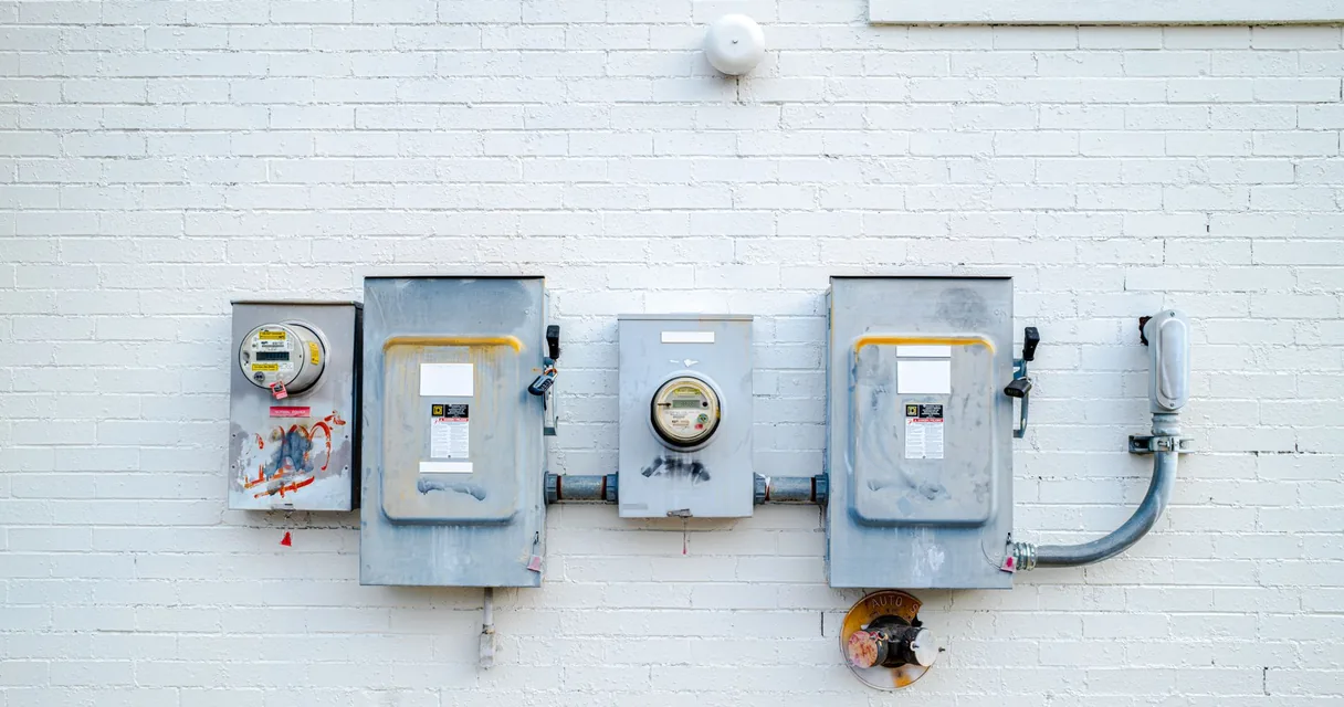 Caixas de medição e medidores de energia fixados em uma parede de tijolos brancos